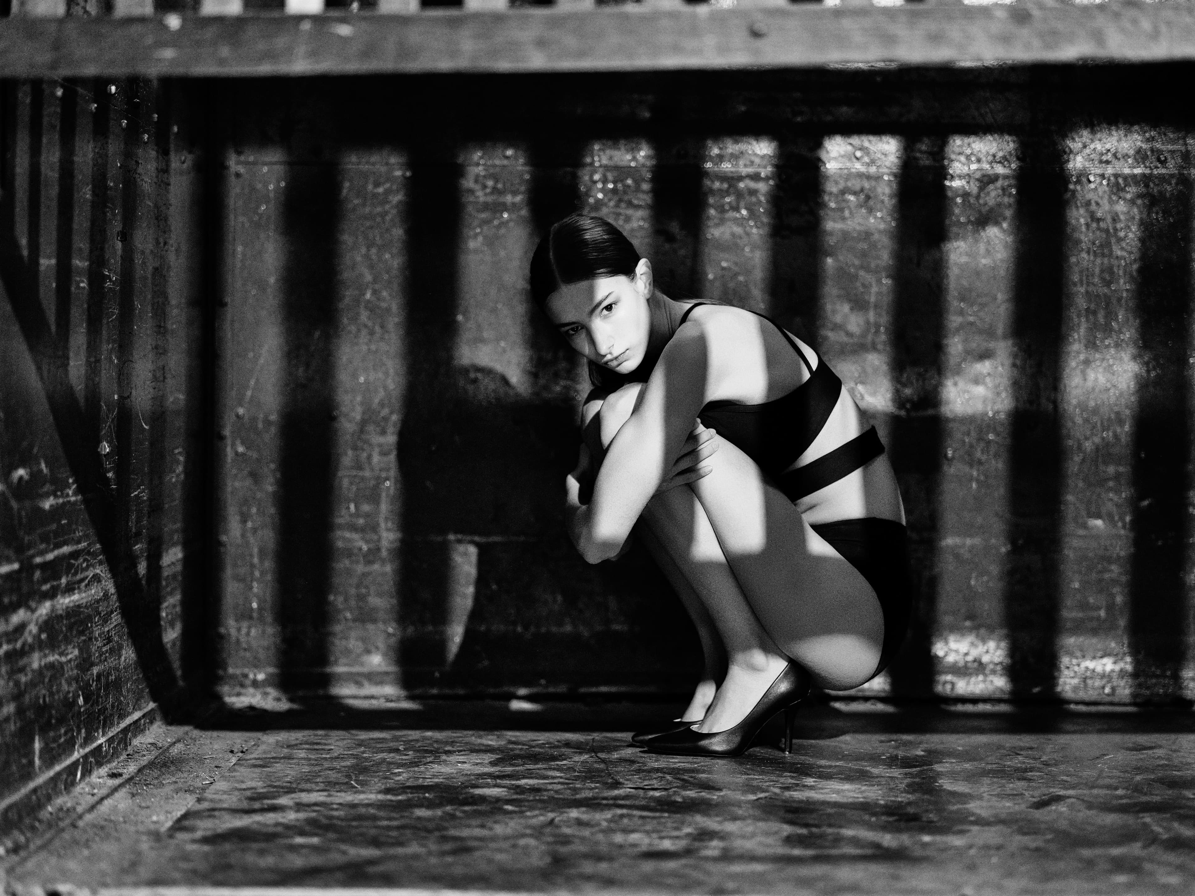 Ava crouching in striped shadow, dramatic hard light study