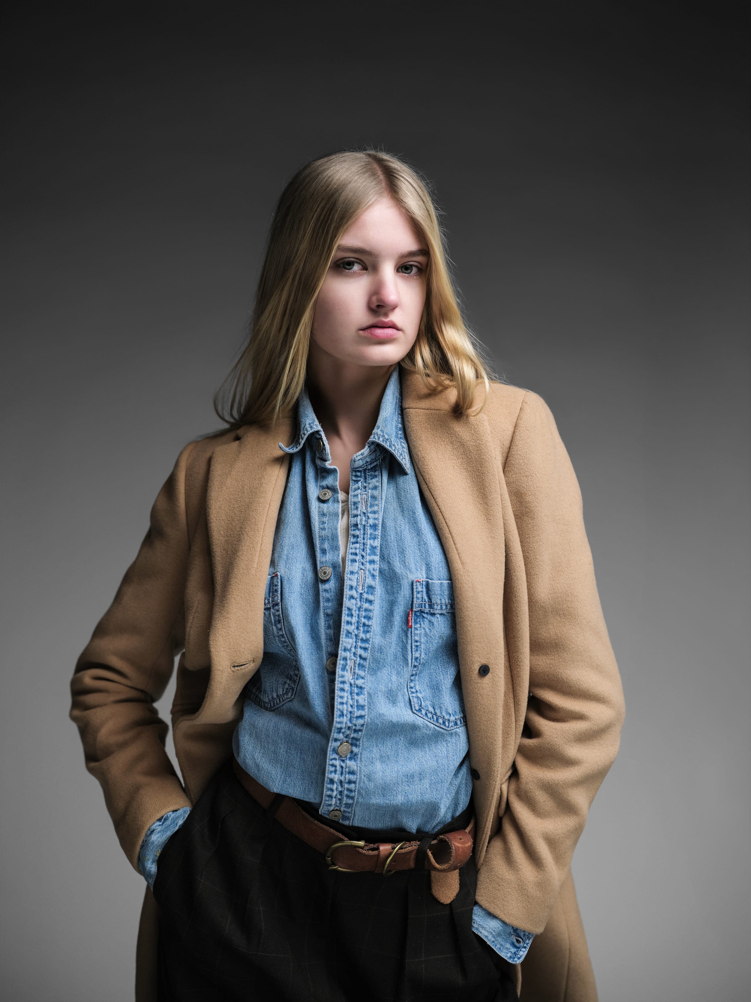 Lydia in an oversized grey blazer over a hoodie, studio, direct gaze
